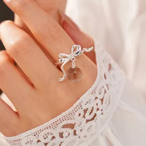 Elegant silver bow open ring with zircon and clear resin bead on finger