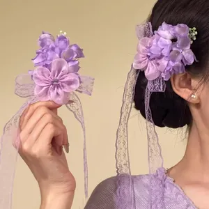 Vista laterale di un elegante fermaglio per capelli con fiori viola e lunghi nastri di pizzo