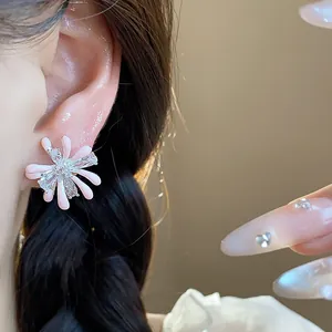 Close-up detail of a pink enamel flower stud earring with zircon stones on an ear