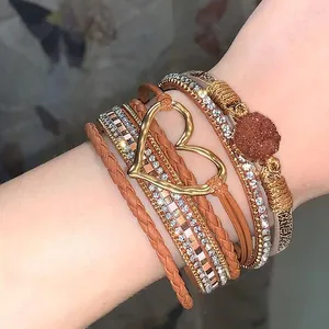 Close-up detail of a Bohemian multi-layer leather bracelet featuring a golden heart charm