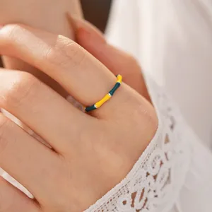 Close-up of vintage bamboo joint ring with yellow and green enamel details on hand.