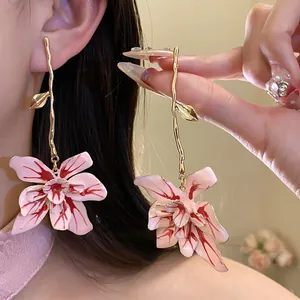 Detail of large pink and red oil-drop flower earrings with long gold stem