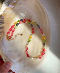 Detail view of colorful crystal and pearl beaded necklace on an iridescent shell.