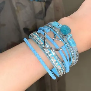 Close-up of bohemian multilayer leather bracelet with metal heart and blue stone