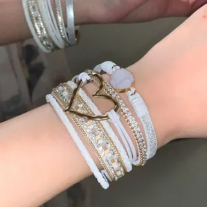 Detail of white multi-layer leather bracelet with golden heart charm and sparkling druzy stone