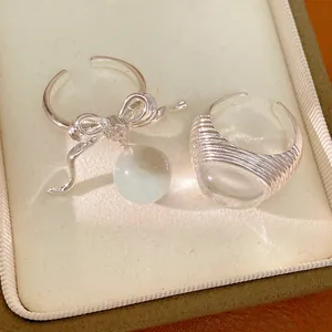 Detailed view of elegant bow ring with resin bead and textured silver band jewelry set