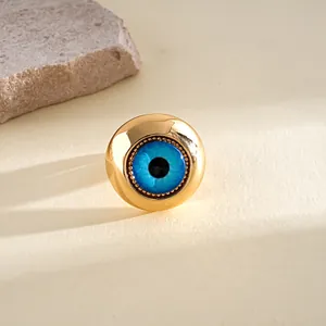 Macro detail of a gold-plated ring featuring a vibrant blue resin evil eye design.