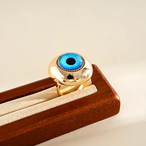 Close-up detail of a blue resin evil eye ring with a polished gold-plated finish.