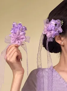 Dettaglio molletta per capelli con fiori viola e nastri di pizzo per un look romantico ed elegante.