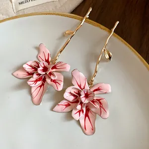 Close-up of pink enamel flower drop earrings with a golden stem for a stylish look