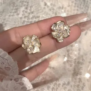 Exquisite detail of French retro style white camellia stud earrings with shimmering crystals.