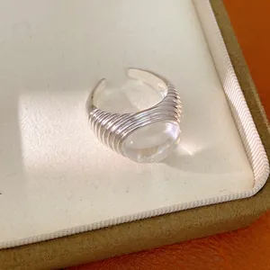 Detailed close-up of a silver-toned open ring with a clear resin bead on a jewelry box.