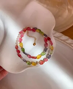 Detailed view of candy-colored crystal and pearl beaded necklace in white shell tray