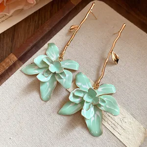 Macro view of elegant mint green floral drop earrings featuring gold branch-like stems