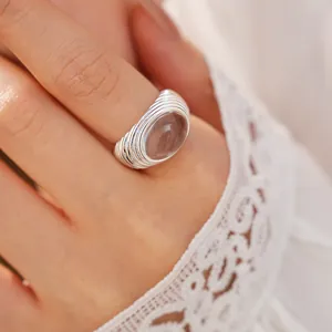 Detailed view of silver ribbed open ring with an oval translucent resin stone on a finger