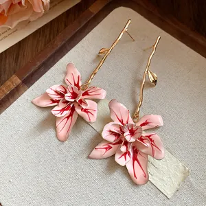 Close-up detail of pink enamel flower drop earrings with elegant gold branch accents