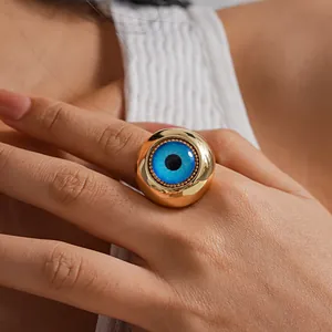 Detailed macro shot of a bold gold-tone adjustable ring featuring a vibrant blue resin evil eye