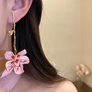 Close-up of a pink oil-drop flower pendant earring worn on an ear, elegant style