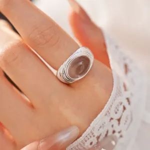 Close-up of a silver-colored ring with an oval translucent stone on a model's finger