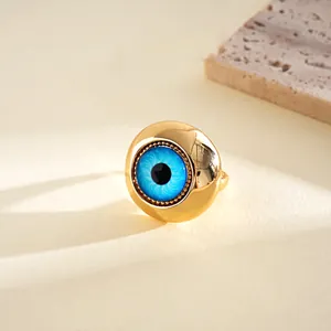 Macro view of a gold evil eye ring with a vibrant blue resin center on a stone base.