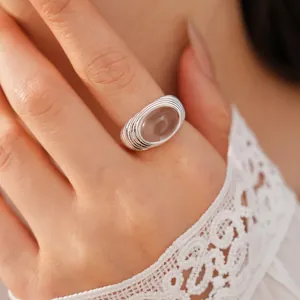 Detail of a silver ribbed ring with a large oval translucent resin stone on a hand