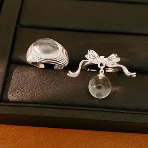Macro view of minimalist silver bowknot open ring featuring a clear resin bead detail