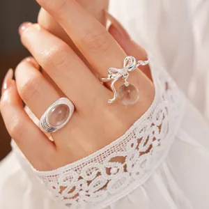 Detail view of silver bow ring with zircon and dangling clear resin bead on model