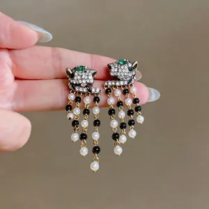 Luxury gold leopard head stud earrings featuring pearl fringe and green eyes