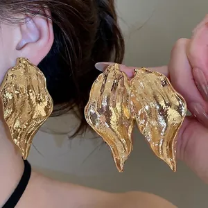Irregular metallic leaf earrings with wrinkled texture in gold and silver finish