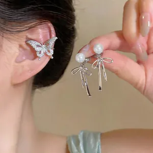 Detailed macro shot of sparkling zircon butterfly ear cuff with pearl bow-knot earrings
