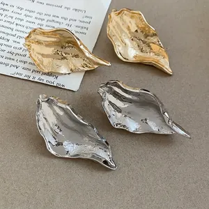 Elegant irregular leaf-shaped metal stud earrings with gold and silver crumpled finish.