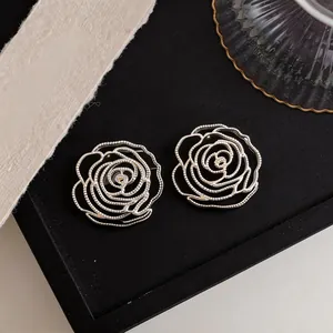 Close-up view showing the intricate beaded texture of silver hollow rose stud earrings