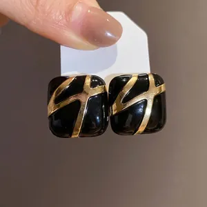 Elegant square black enamel stud earrings with gold geometric pattern on silver needles