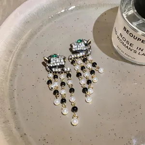 Detailed view of luxury leopard head earrings with pearl tassels and crystal embellishments