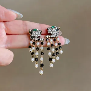 Detailed close-up of leopard head earrings with shimmering crystals and pearl tassels.