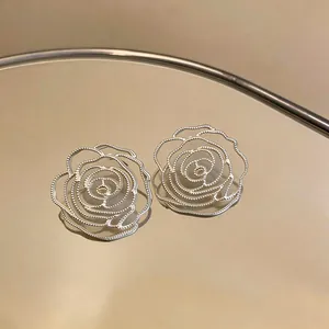 Close-up of silver hollow out rose flower stud earrings with intricate bead edge details