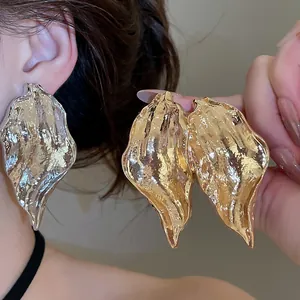 Close-up of irregular wrinkled leaf earrings with high-shine metallic texture
