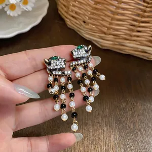 Detailed view of luxury vintage panther head earrings with pearl and black bead tassels