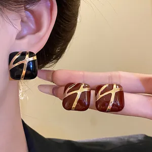 Close-up detail of elegant square enamel stud earrings featuring gold cross design