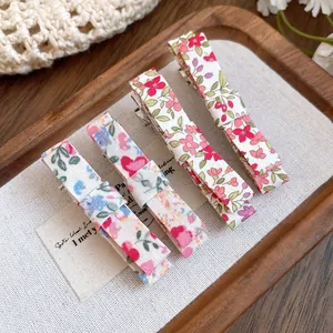 Close-up of four Mori style floral fabric hair clips on a wooden display tray