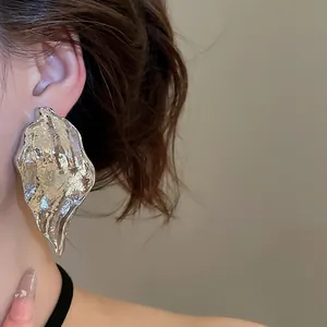 Close-up of silver irregular wrinkled leaf-shaped metallic earrings for women