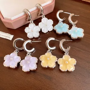Dettaglio di orecchini a forma di fiore in resina colorata con perni in argento e perle.
