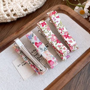 Close-up detail of four Mori-style floral fabric duckbill hair clips on a wooden tray.
