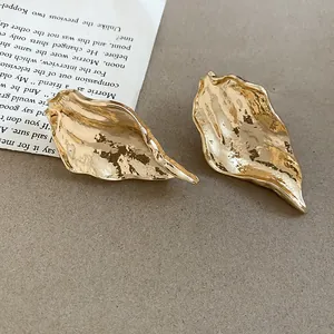 Detailed view of gold-tone irregular leaf earrings with a textured metallic finish.