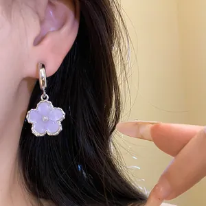 Dettaglio ravvicinato di un elegante orecchino a fiore in resina viola con perla centrale