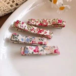 Close-up of four floral pattern fabric hair clips on a white ceramic plate.