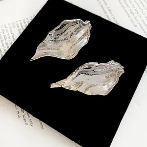 Detail shot of silver leaf earrings with unique irregular pleated metallic texture