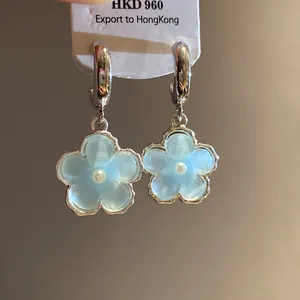 Vista dettagliata degli orecchini a fiore in resina blu chiaro con perle e cerchi