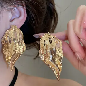 Close-up of gold irregular leaf earrings with hammered texture and vintage finish.