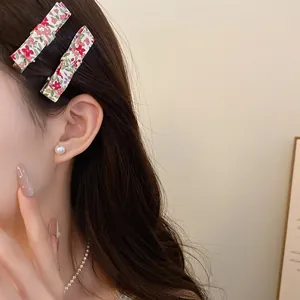 Detail view of a floral fabric hair clip worn on long wavy brown hair for a sweet look.